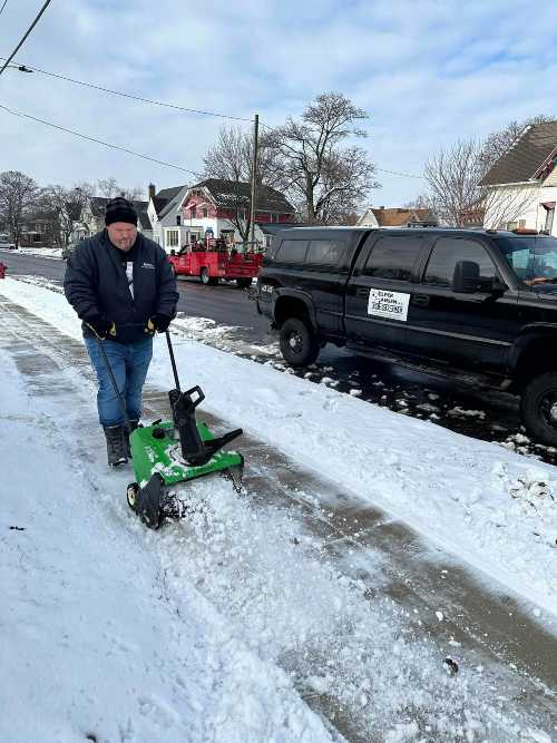 Aaron snow blowing a sidewalk.